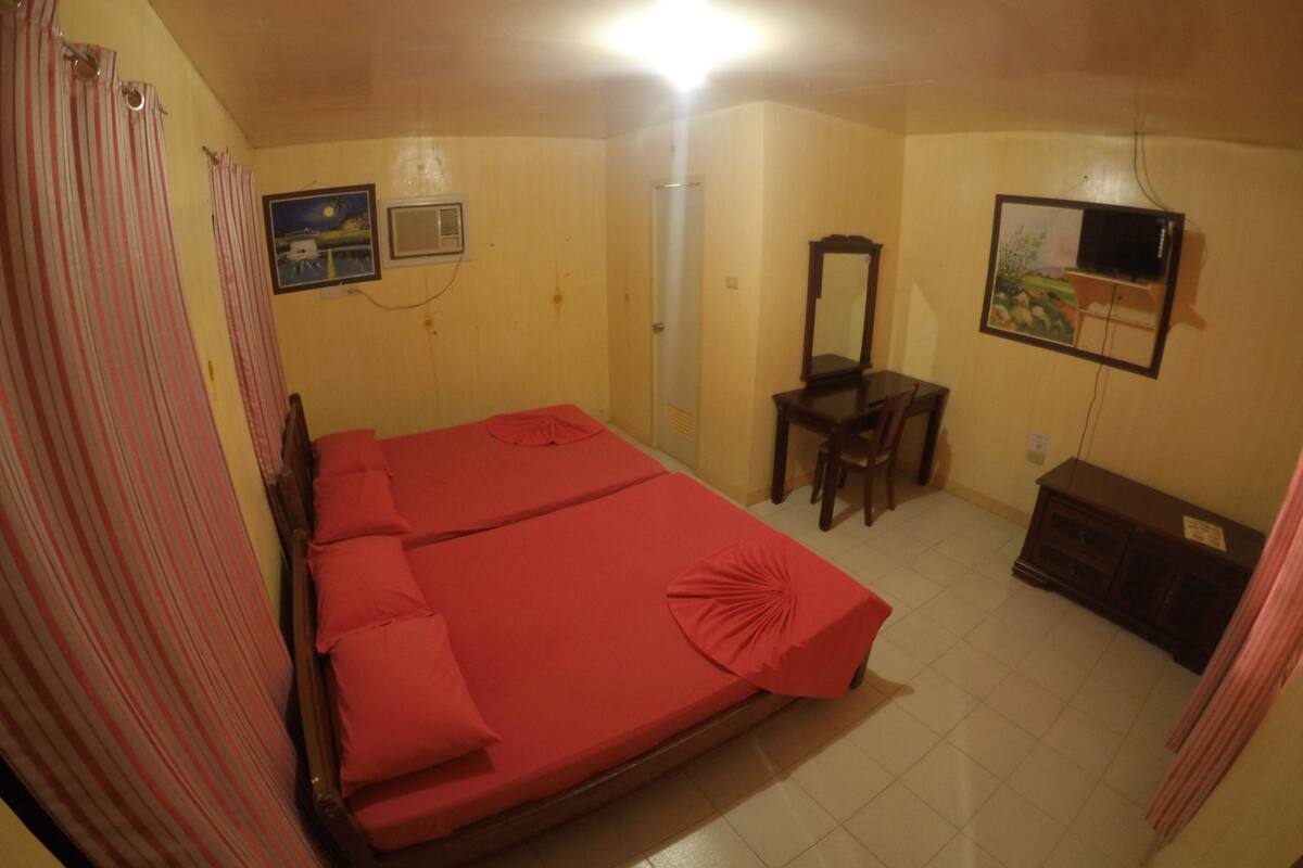 A bedroom with a bed, a desk, a chair, a TV, and a wardrobe.