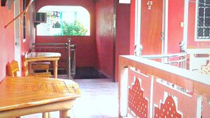 A room with a wooden table and chairs, a window with a view, a red door, and a kitchen area with a sink and countertop. - Buena Lynne's Resort Annex (Puerto Galera)