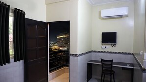 A room with a desk, chair, and an air conditioning unit on the wall.