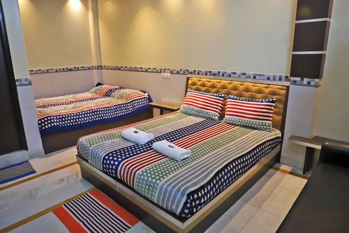 A hotel room with two beds, each with a distinct patterned bedspread.