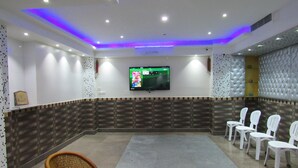 A conference room with a flat-screen TV, white chairs, and a patterned wall.