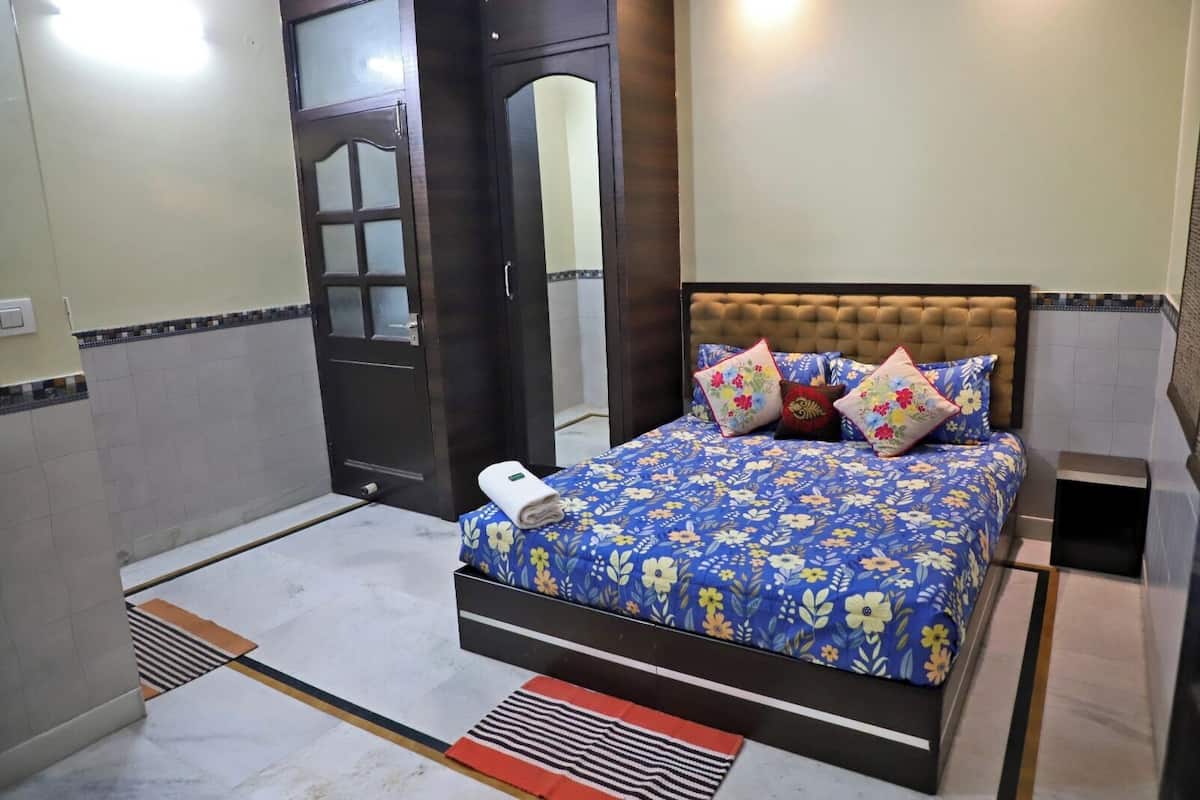 A bedroom with a bed, a door, and a small bedside table.