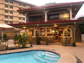 Un hotel con piscina, zona de estar al aire libre y bar.
