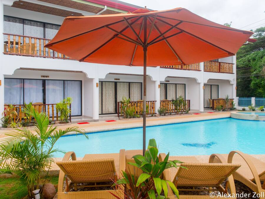 Una piscina al aire libre, sombrillas, sillones reclinables de piscina