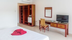 A hotel room with a bed, a desk with a chair, a television, a wardrobe, and a mirror. - Alona Vida Beach Hill (Panglao)