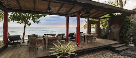 A wooden deck with wicker furniture and a potted plant, overlooking a body of water.