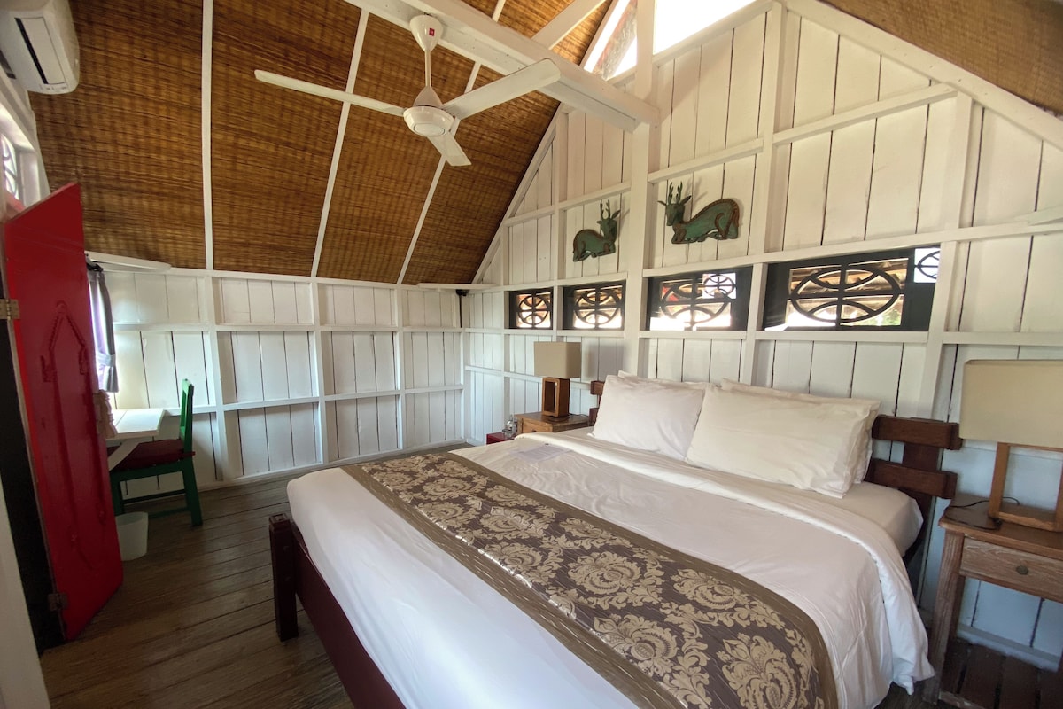 Ein Zimmer mit einem großen Bett, einem Deckenventilator, Holzwänden und Wanddekoration.