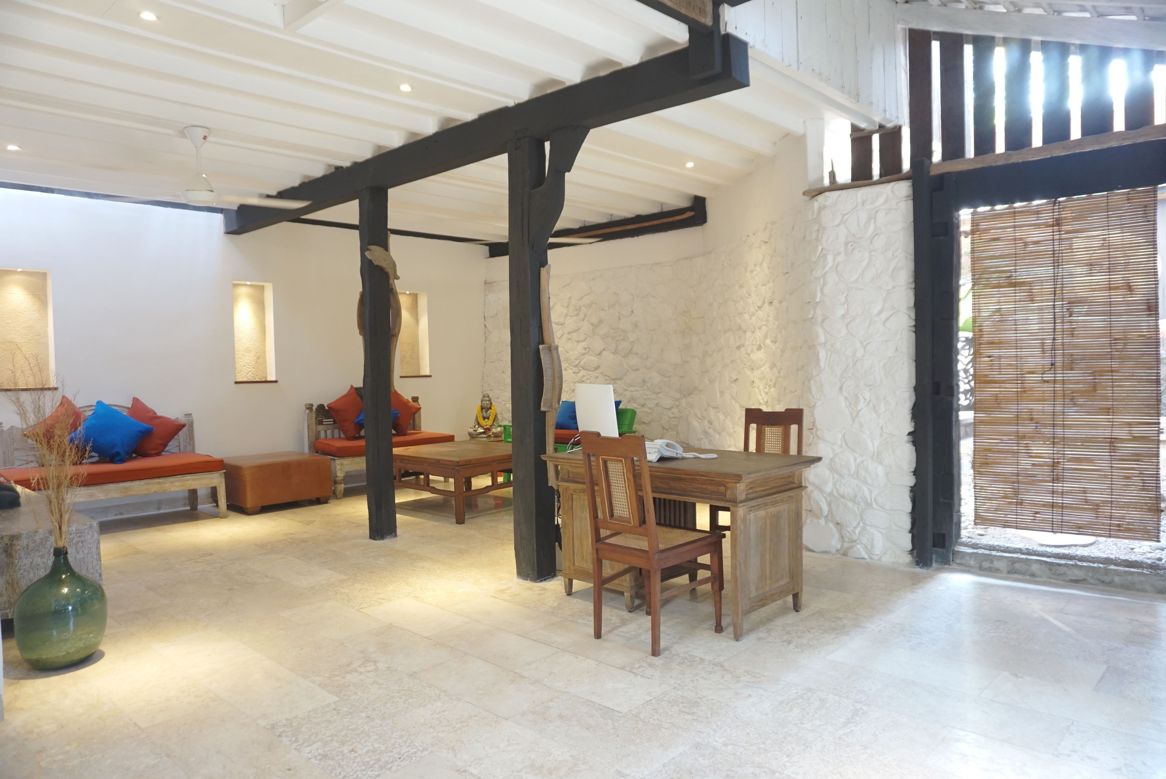 Un amplio salón con pared de piedra, muebles de madera y un gran ventanal con persianas.