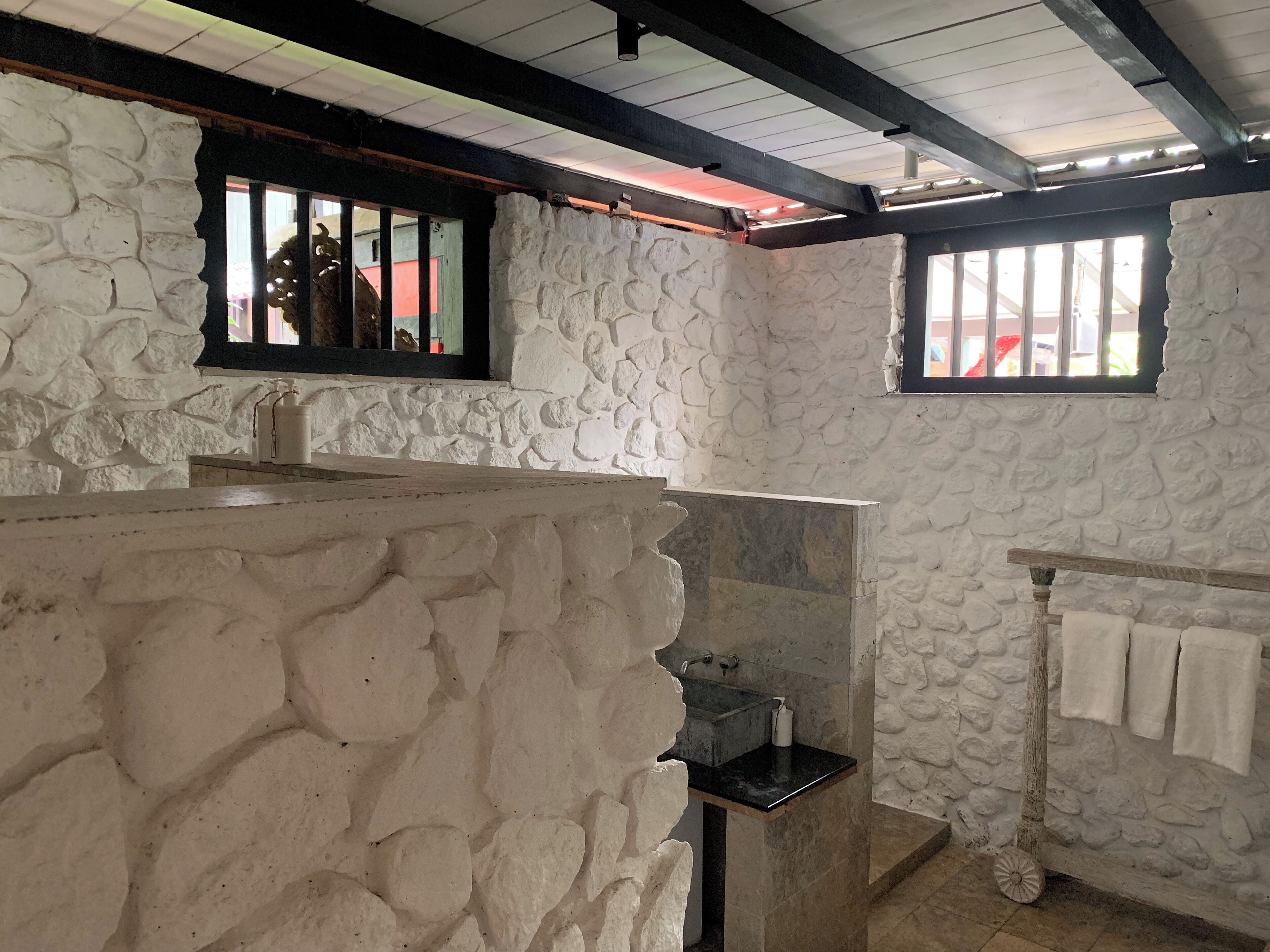 A bathroom with stone walls, a sink, and a window with a view.
