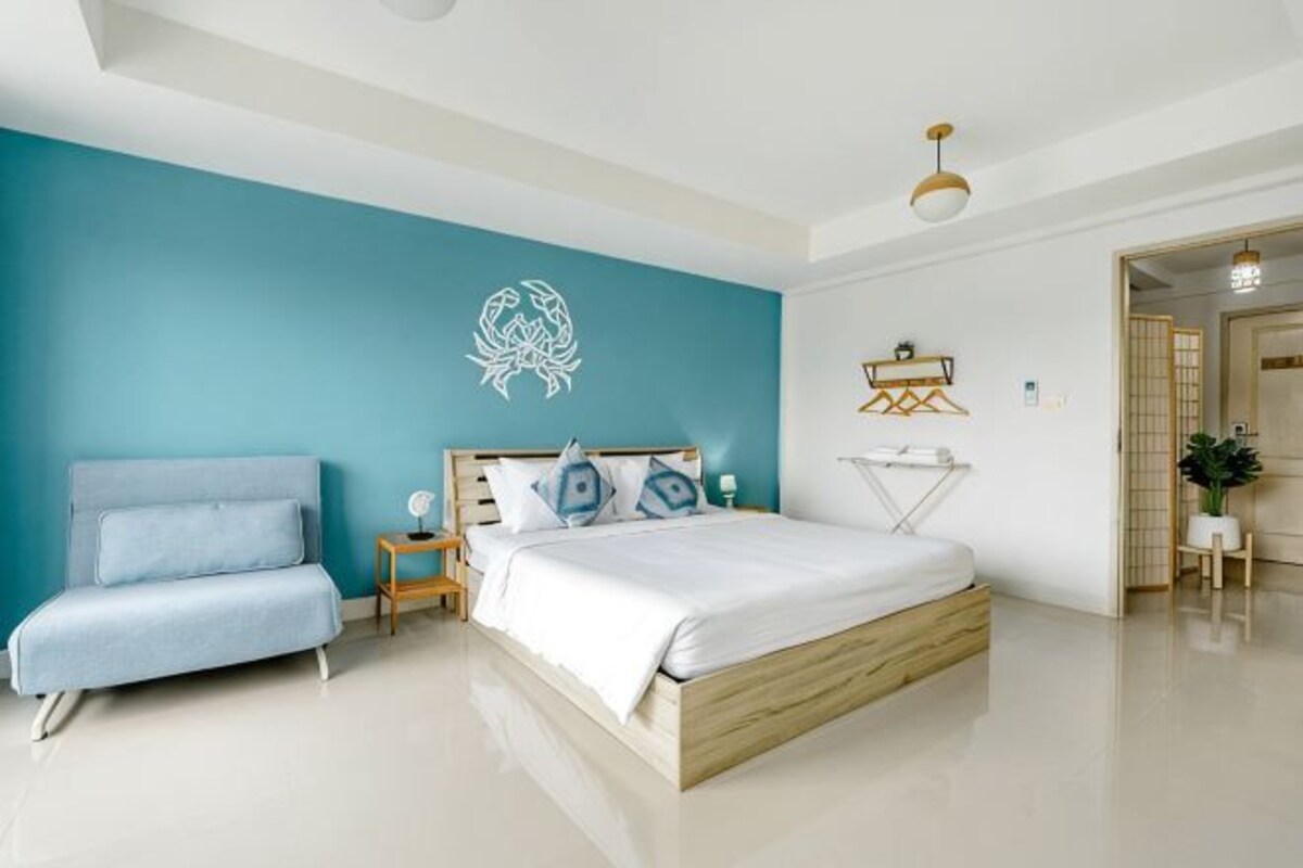 Un dormitorio con cama, sofá, mesita de noche y una obra de arte en la pared.