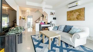 Een moderne woonkamer met een witte bank, een bijzettafeltje en een vloerkleed met een patroon.