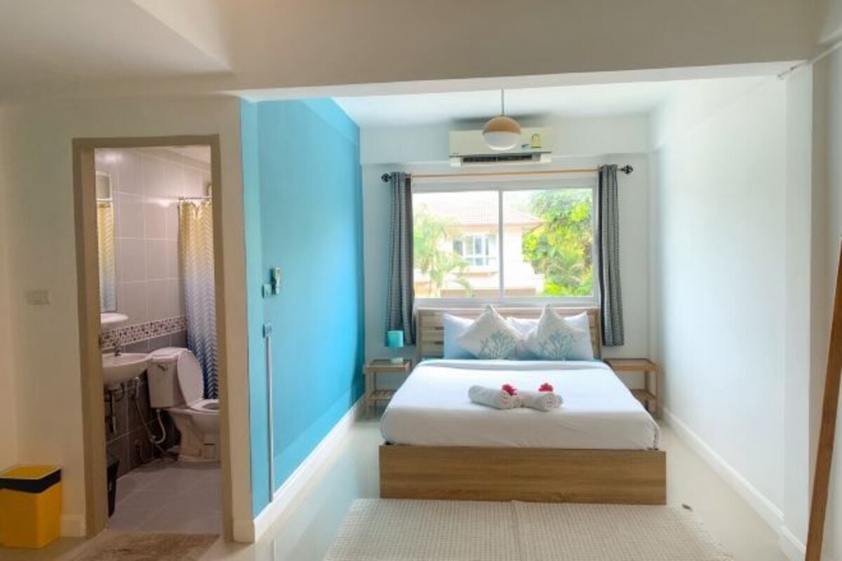 Un dormitorio con cama, ventana, baño y ventilador de techo.