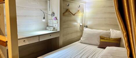 Une chambre à coucher comprenant un lit, une table de chevet, un miroir et un luminaire fixé au mur.