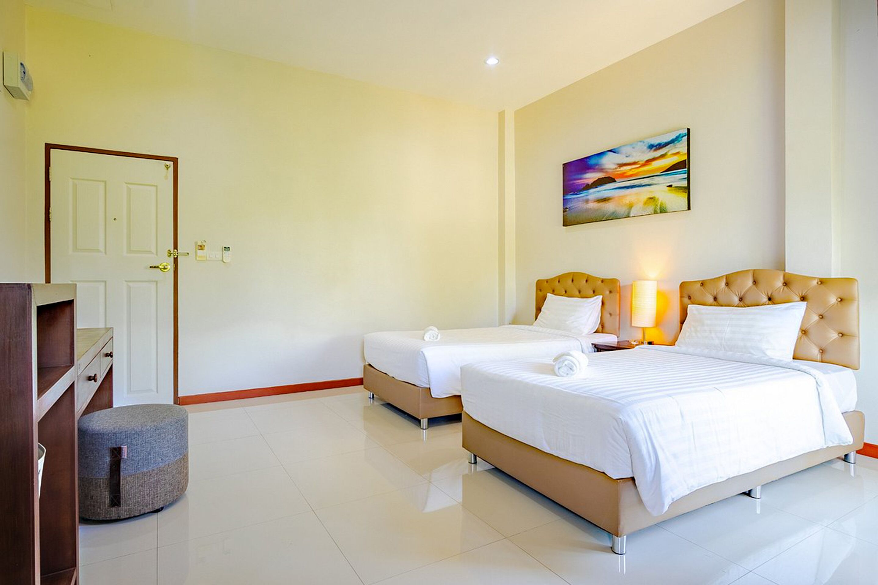 A hotel room with two beds, a desk, and a chair.