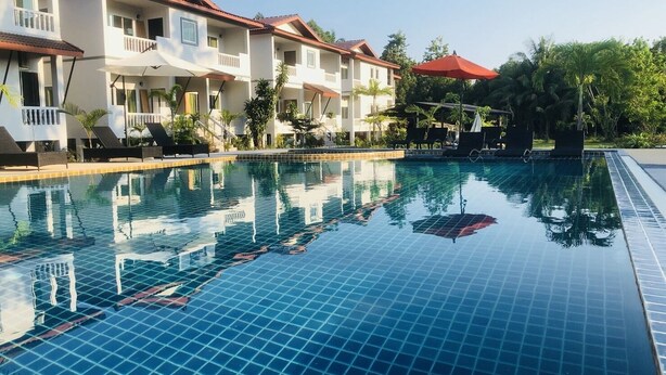 Una piscina con suelo de baldosas, rodeada de edificios de varios pisos con balcones y techos rojos.