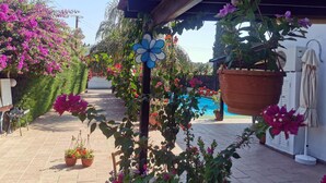 Ein überdachter Außenbereich mit Pool, umgeben von Kübelpflanzen und Blumen.