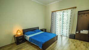 Une chambre à coucher avec un lit, des tables de chevet, une lampe, une armoire et une fenêtre avec des rideaux.