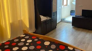 Ett sovrum med en säng, en garderob, en tv och ett badrum som syns genom en öppen dörr.