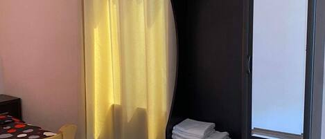 Un dormitorio con cama, cabecera de madera, armario y ventana con cortinas.