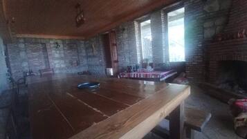 Un interior rústico con una mesa de madera, paredes de piedra y una chimenea.