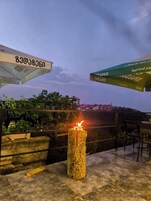 Una terraza con una mesa, sillas, una chimenea y vistas a un pueblo lejano.