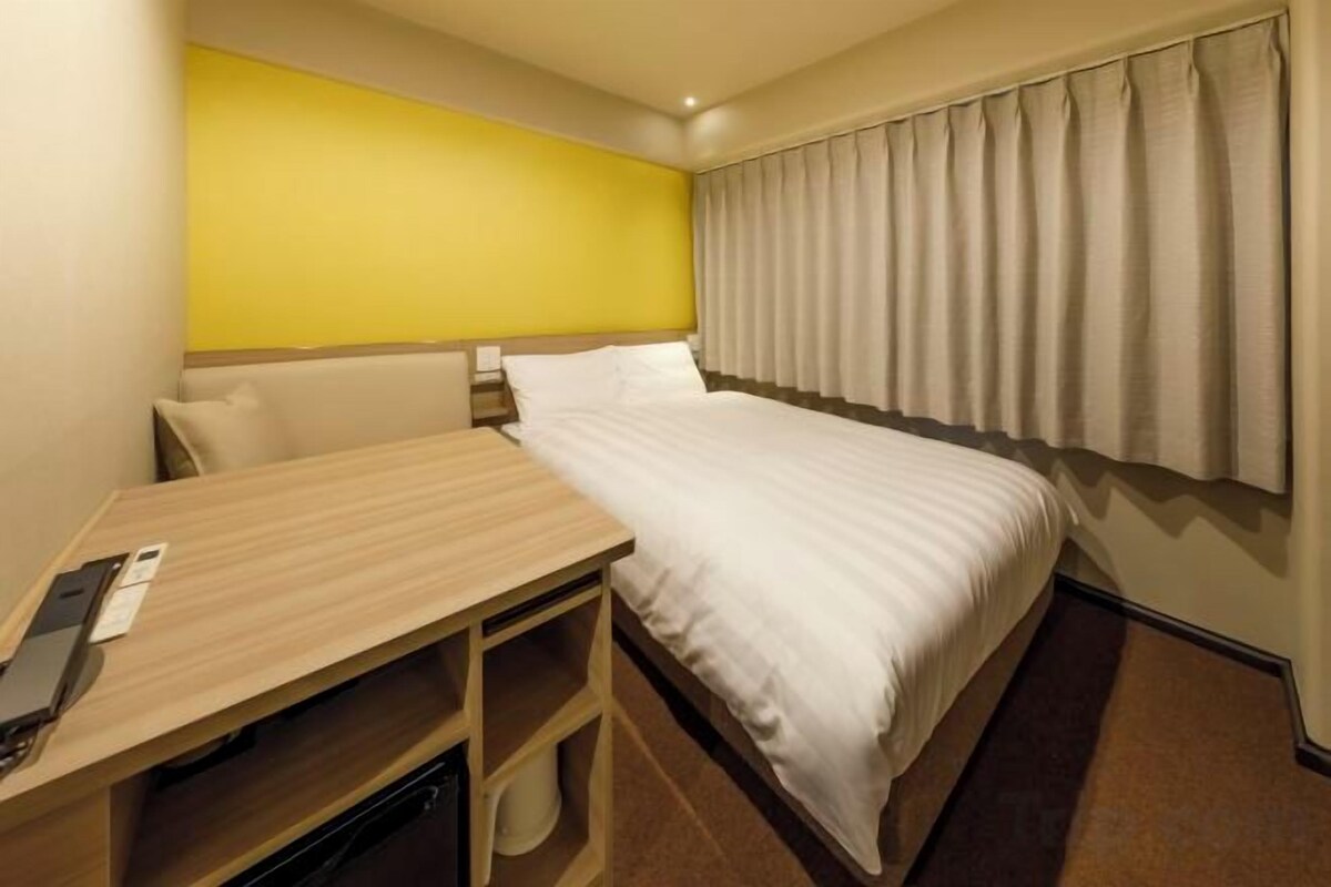 A hotel room with a bed, a desk, and a chair.