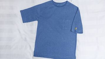 Una camiseta azul lisa con un bolsillo y un pequeño logo en la manga.