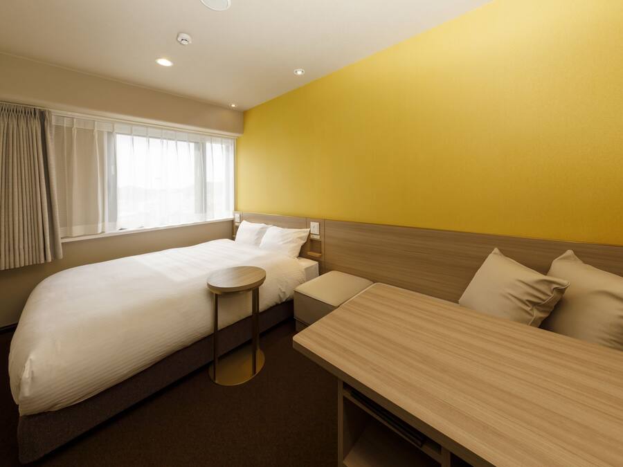 A hotel room with a bed, a small table, and a sofa.