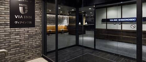 A hotel entrance with a modern design, featuring a brick wall and glass doors.
