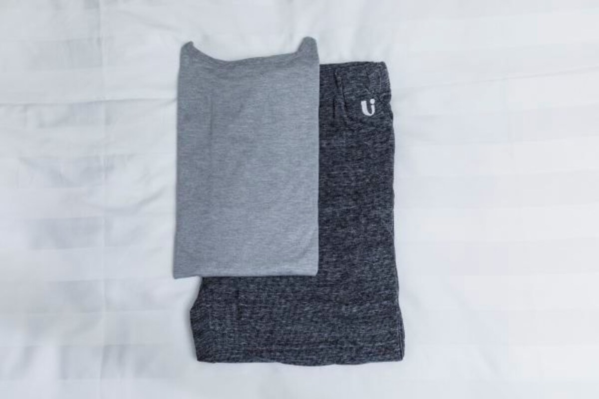 En prydligt vikt, grå och mörkgrå t-shirt med en liten vit logotyp på ärmen.