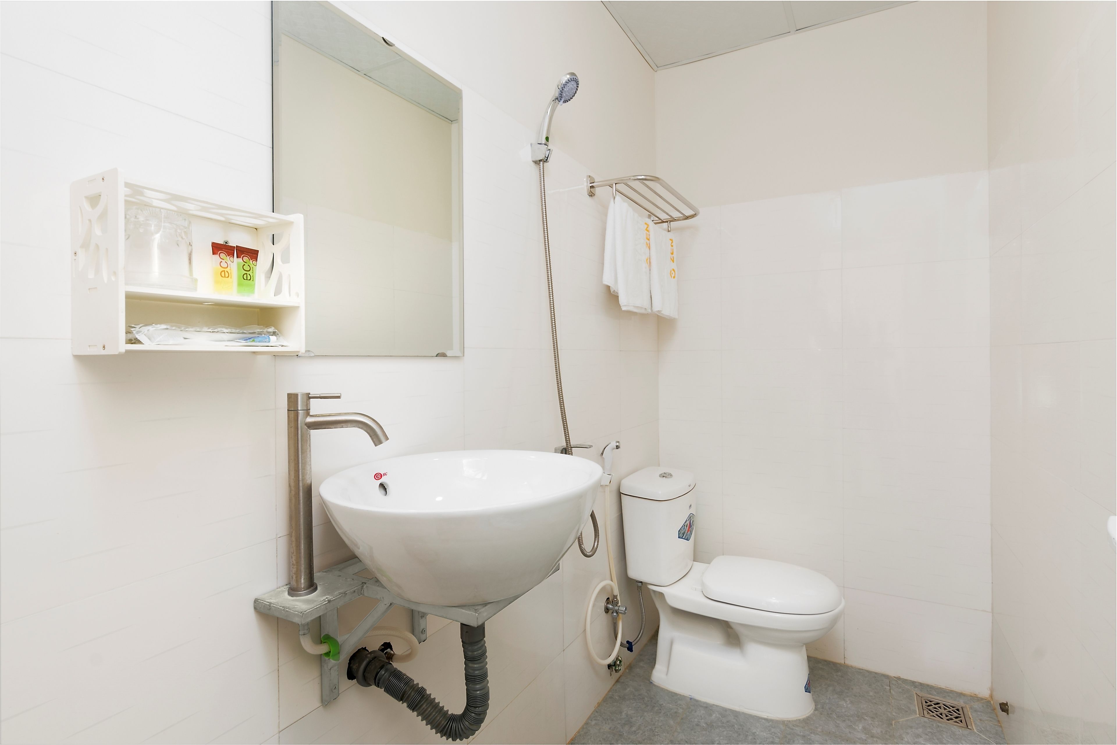 A bathroom with a white sink, toilet, and a shower head.
