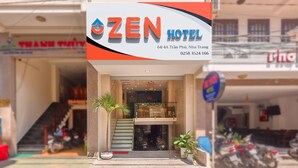 The exterior of the Zen Hotel, featuring a modern facade, a staircase leading to the entrance, and a visible parking area with motorcycles. - Zen Hotel (Nha Trang)