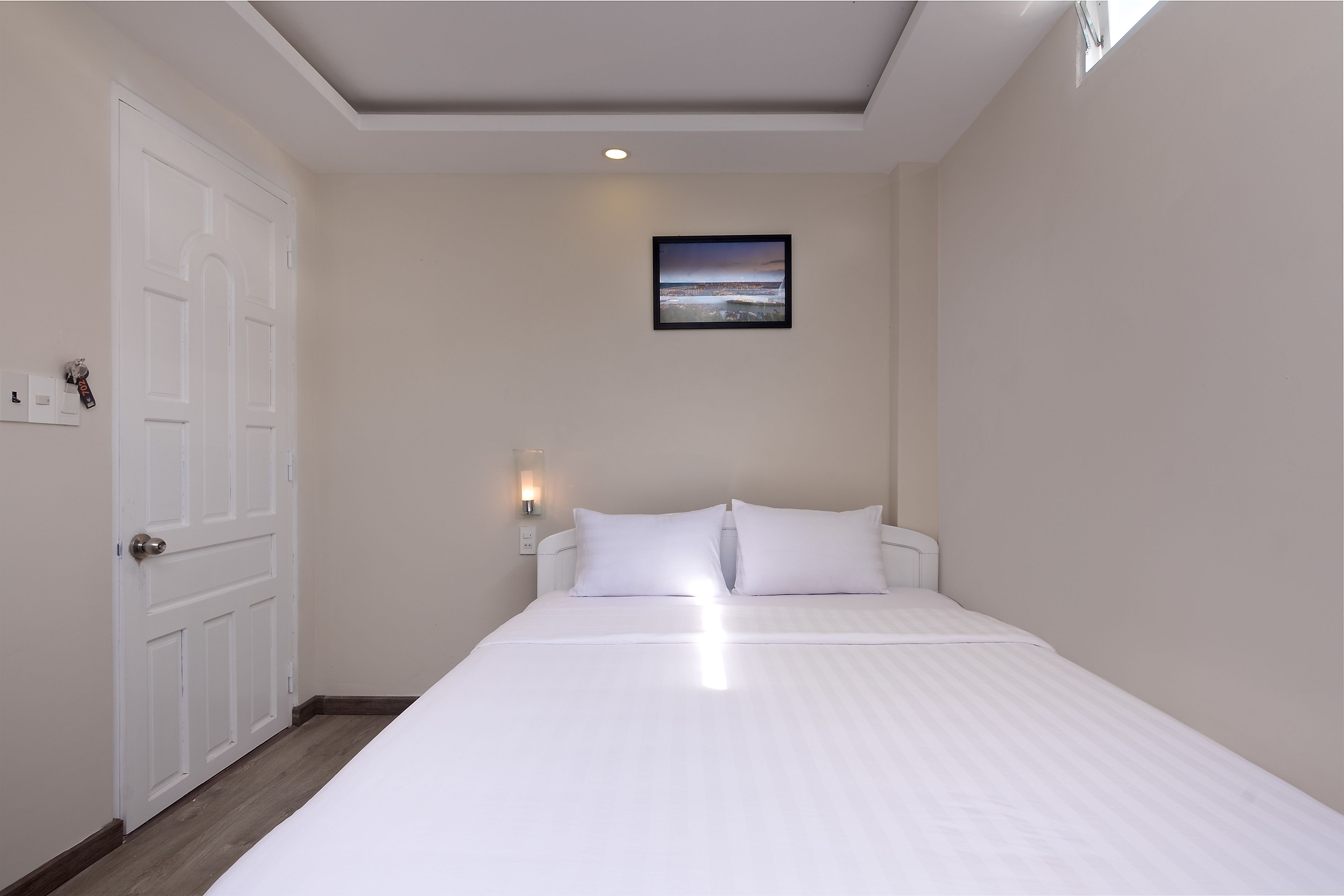 A bedroom with a bed, a door, a wall-mounted picture, and a nightlight.