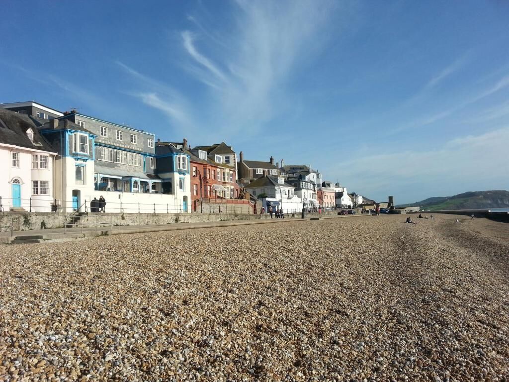 A pebble beach with buildings along the shore.
