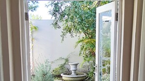 Une porte donnant sur un jardin agrémenté d’un chemin de pierre, d’un vase décoratif et d’un paillasson.