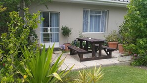 A house with a patio, a wooden table, and potted plants.