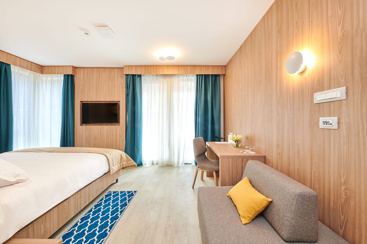 Une chambre d’hôtel avec un lit, un canapé, un bureau et une télévision.