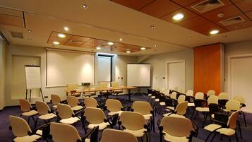 A conference room with rows of chairs, a projector screen, and a whiteboard.