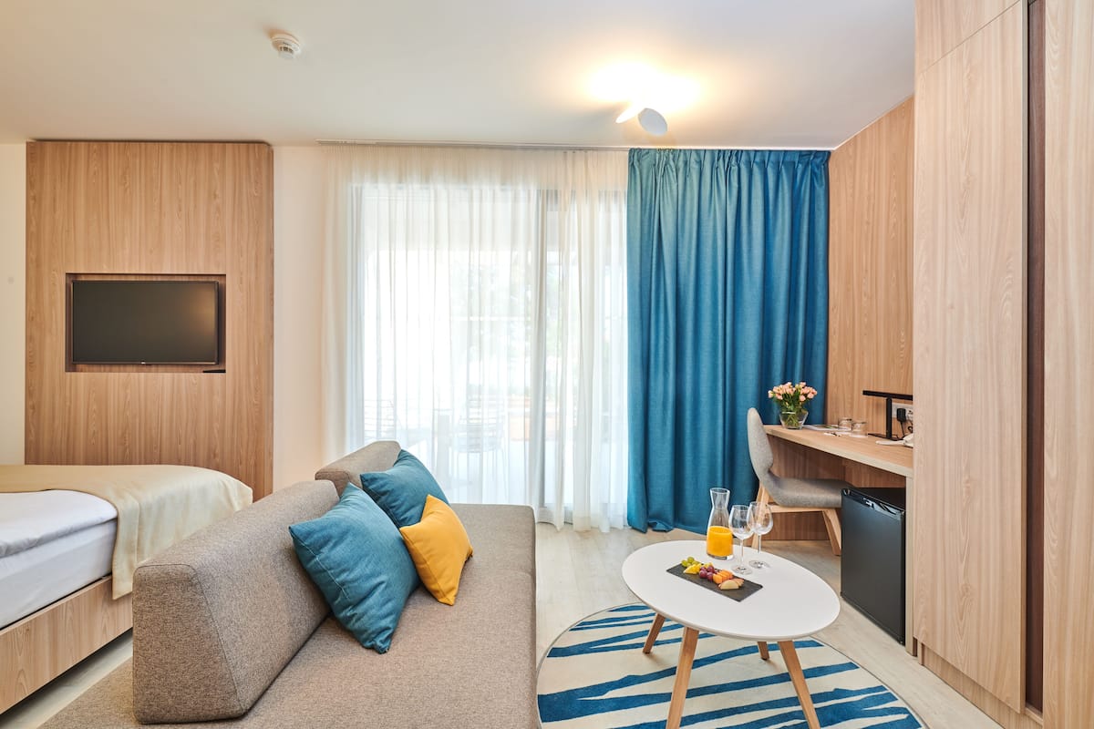 Une chambre d’hôtel moderne équipée d’un canapé, d’une petite table à manger, d’une télévision et d’un coin cuisine.