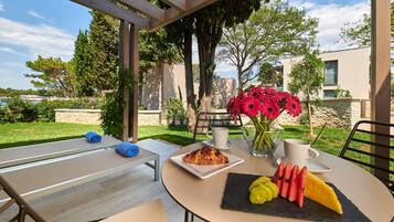 A table set outdoors with a croissant, fruit, and flowers.