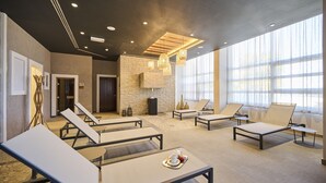 Un espacio lounge moderno con sillones, una pared de piedra y un gran ventanal que proporciona luz natural.