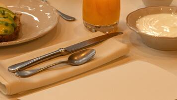 A breakfast setting with croissants, fruit, orange juice, yogurt, and a menu titled "DESAYUNO".