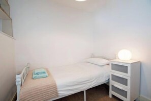 A single bed with a bedside table and lamp, a small bedside table with a lamp, and a wall-mounted shelf. - Toast Stays - Two Clovers at The Grove (Durham)