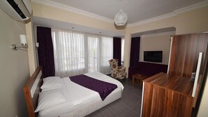 A hotel room with a large bed, a wooden desk, a chair, and a TV. - Hotel Feryıl Liman (Fethiye)