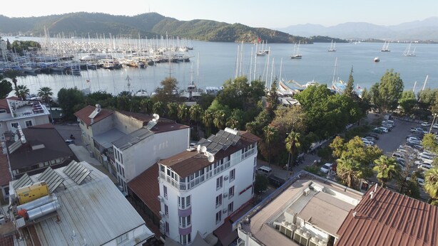A marina with numerous sailboats, surrounded by residential buildings with solar panels on rooftops. - Hotel Feryıl Liman (Fethiye)