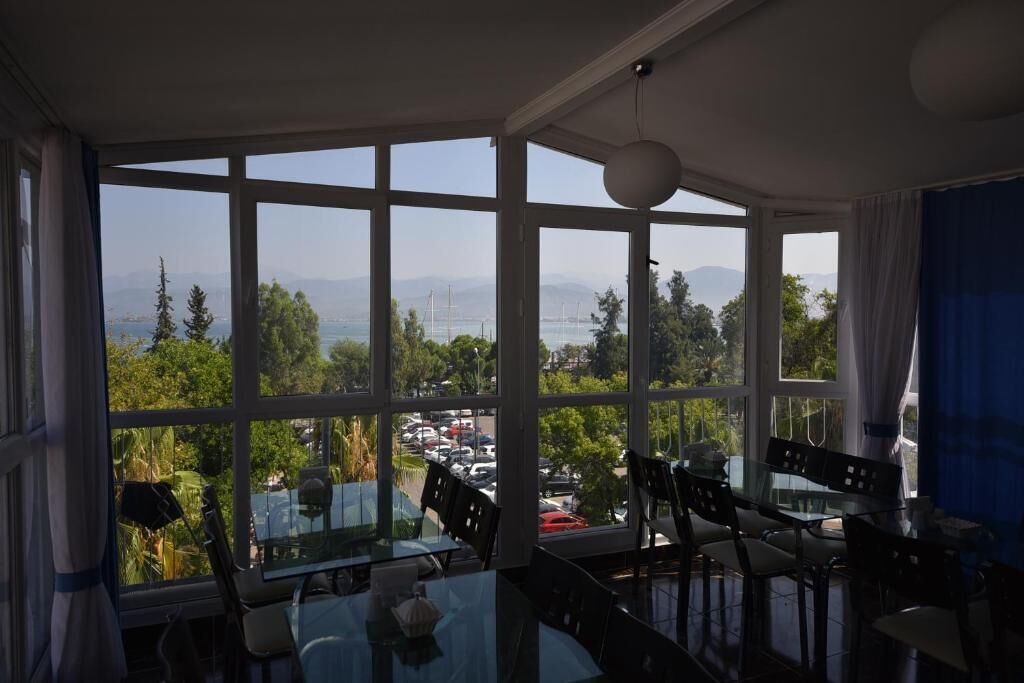 A dining area with a large window offering a view of a parking lot and greenery.
