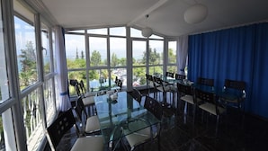 A sunlit dining area with large windows, a glass table, and chairs. - Hotel Feryıl Liman (Fethiye)