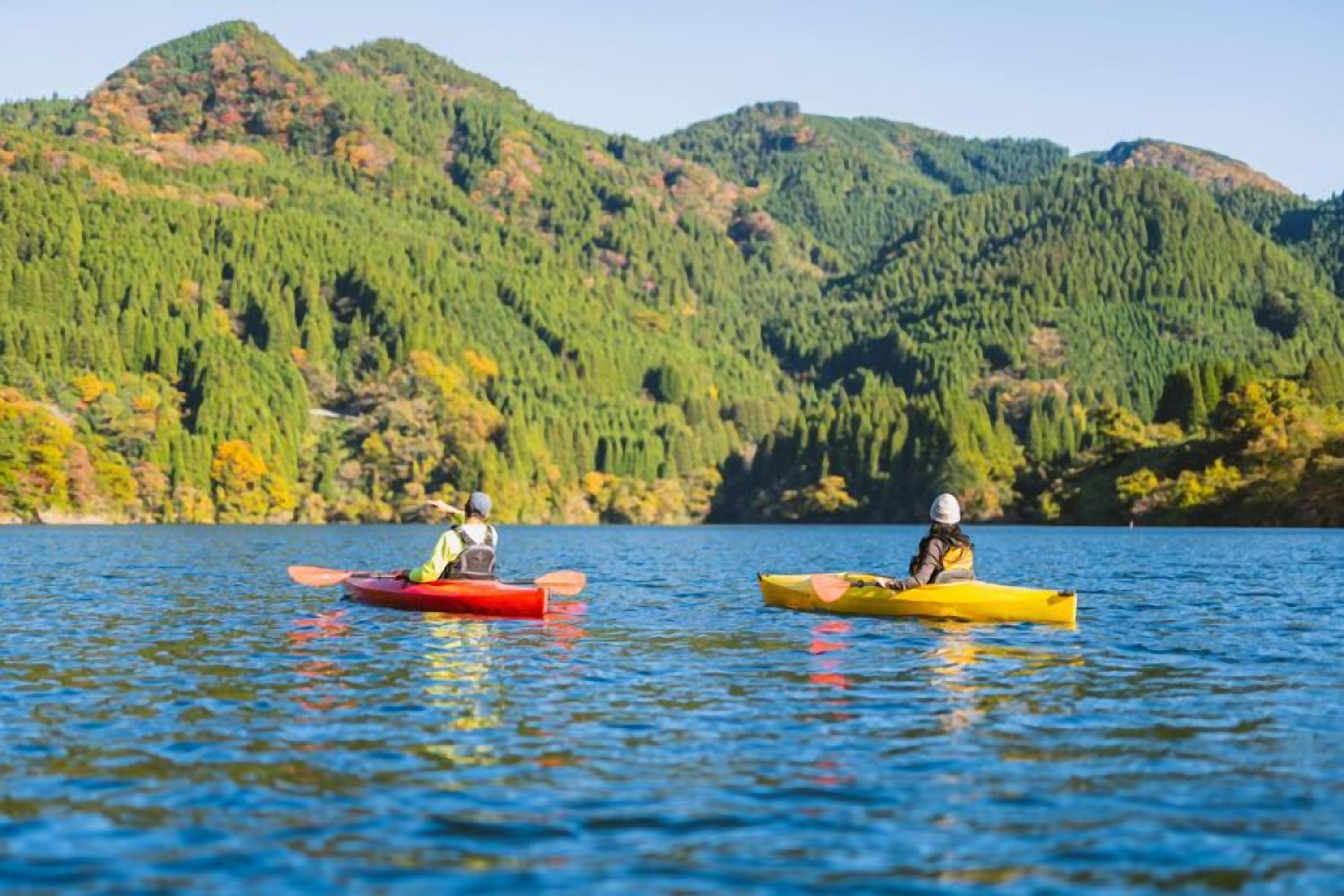 Dos caiacs en un llac tranquil amb turons boscosos al fons.
