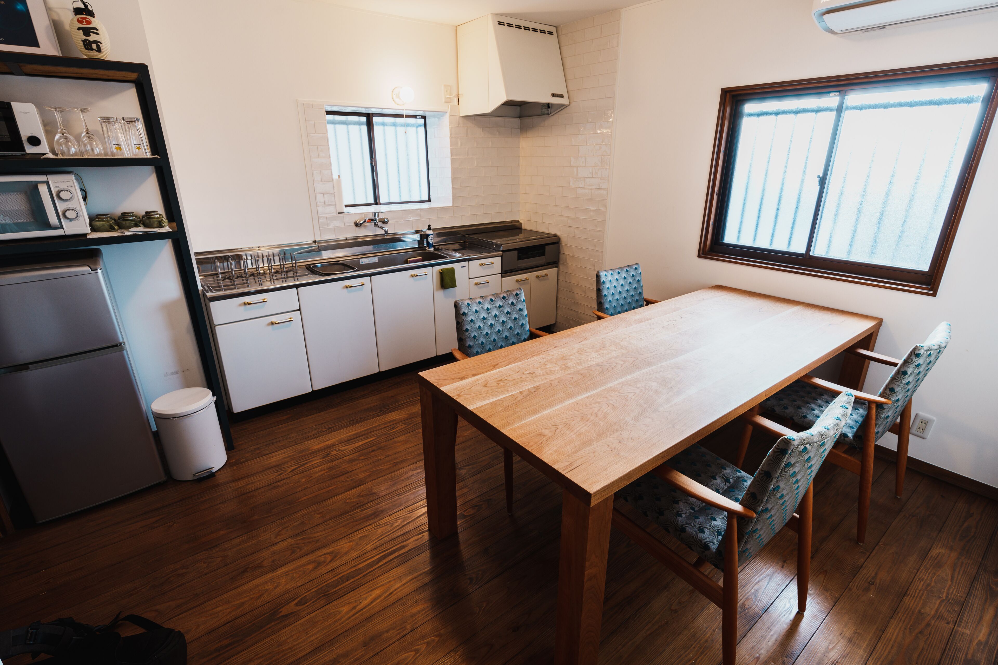 Una cocina compacta con comedor, suelo de madera y una ventana que proporciona luz natural.