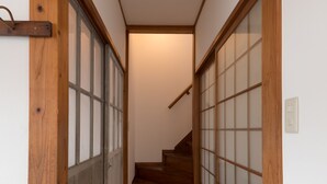 Un pasillo estrecho con suelo de madera y una escalera de madera que sube a un nivel superior.